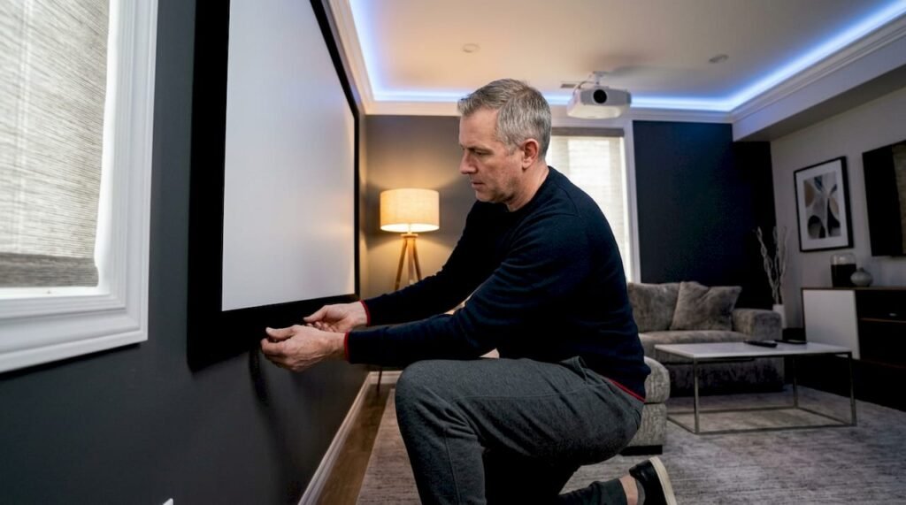 Man adjusting fixed frame home theatre screen