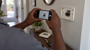 Photographing the wiring behind a thermostat before removing it.