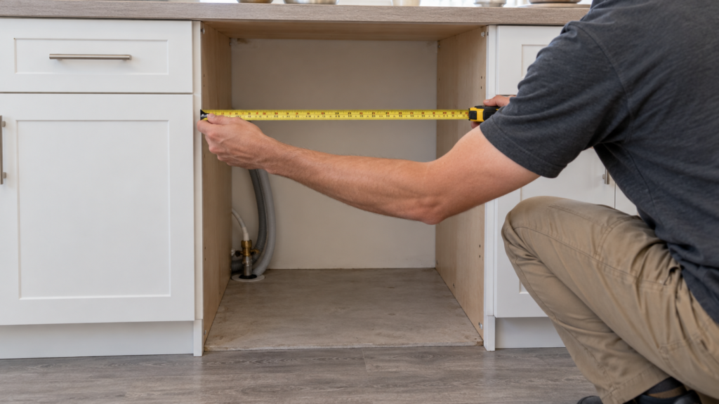 An installer measuring an empty dishwasher opening.